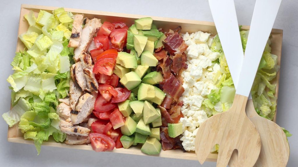 Uma salada fresca e colorida com pedaços de frango macio, verduras mistas e legumes variados.
